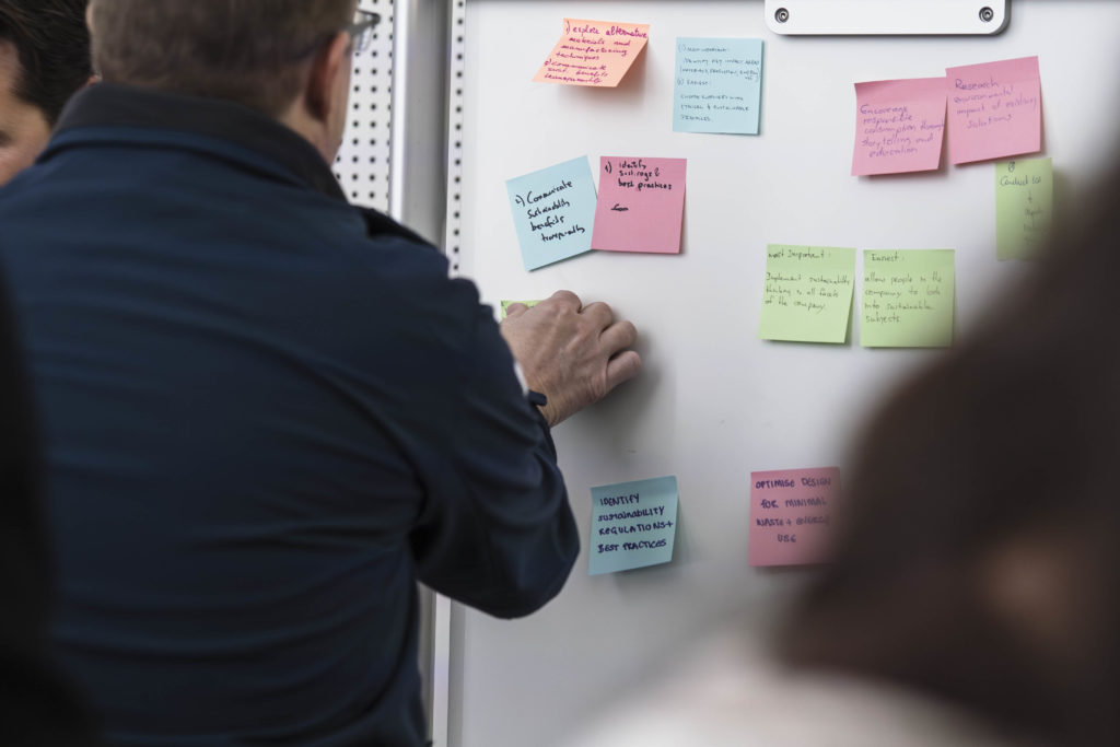 Attendee of 2025 Marine Impact Lab at Metstrade places a post-it on a white board as a part of a sustainability group activity. © 11th Hour Racing | polaRYSE